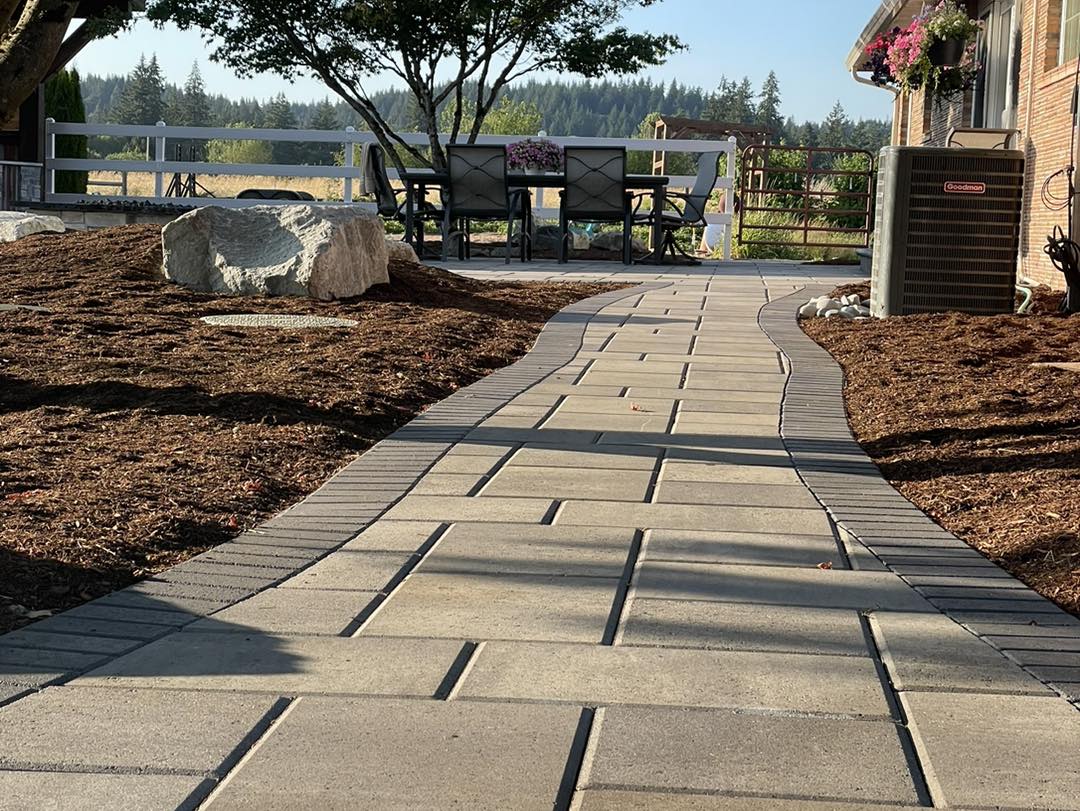 A walkway with brick pavers leading to a bench.