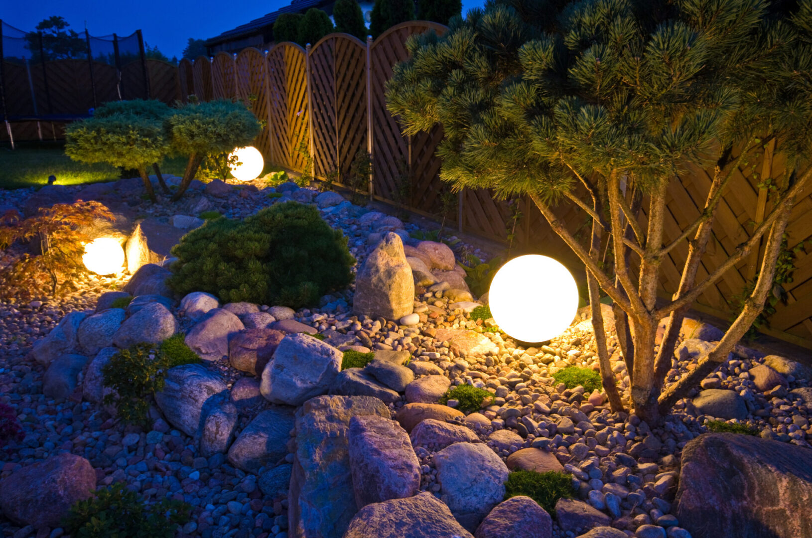 A garden with rocks and lights in the night.