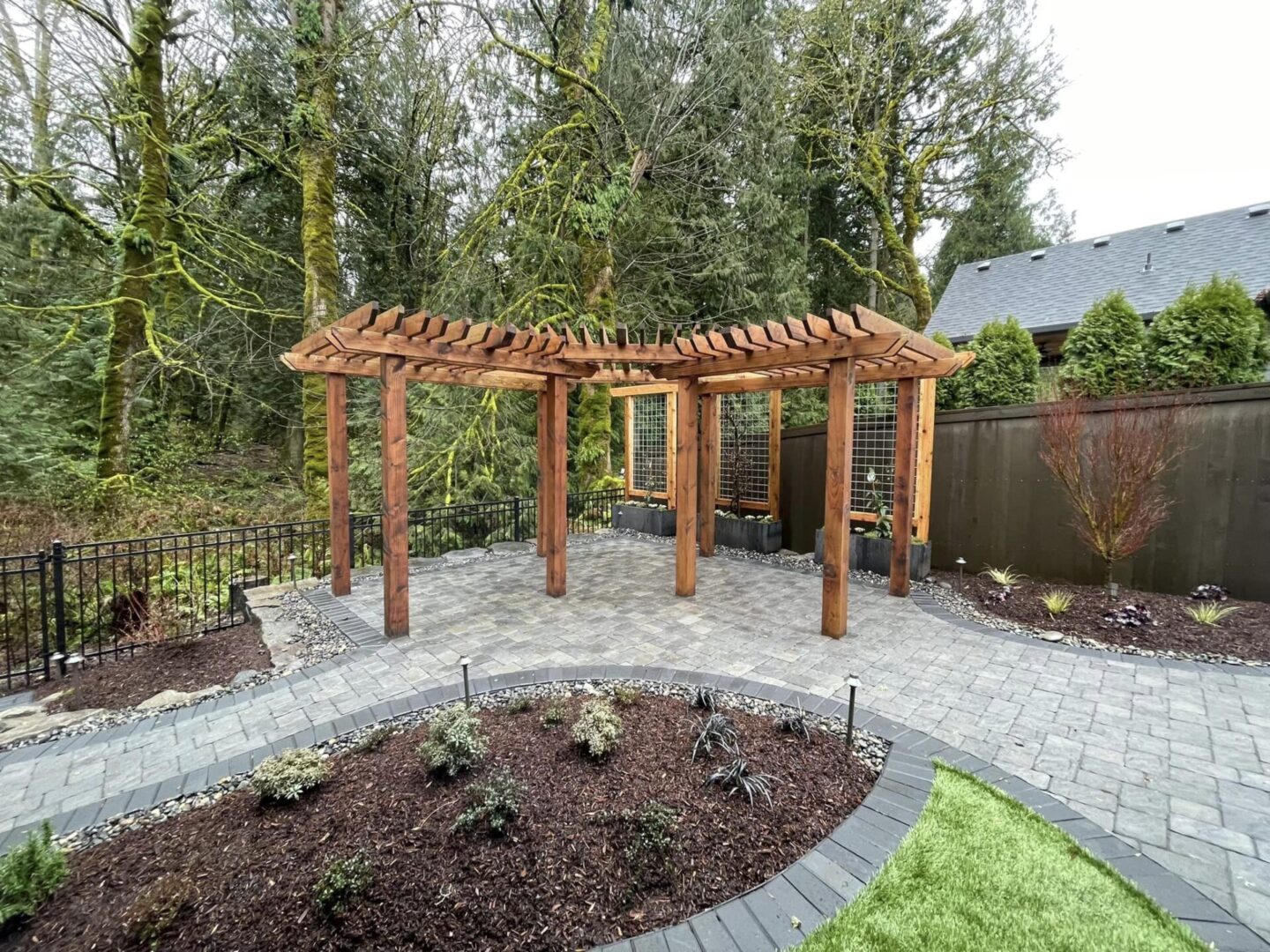 A garden with a large wooden pergola and a flower bed.