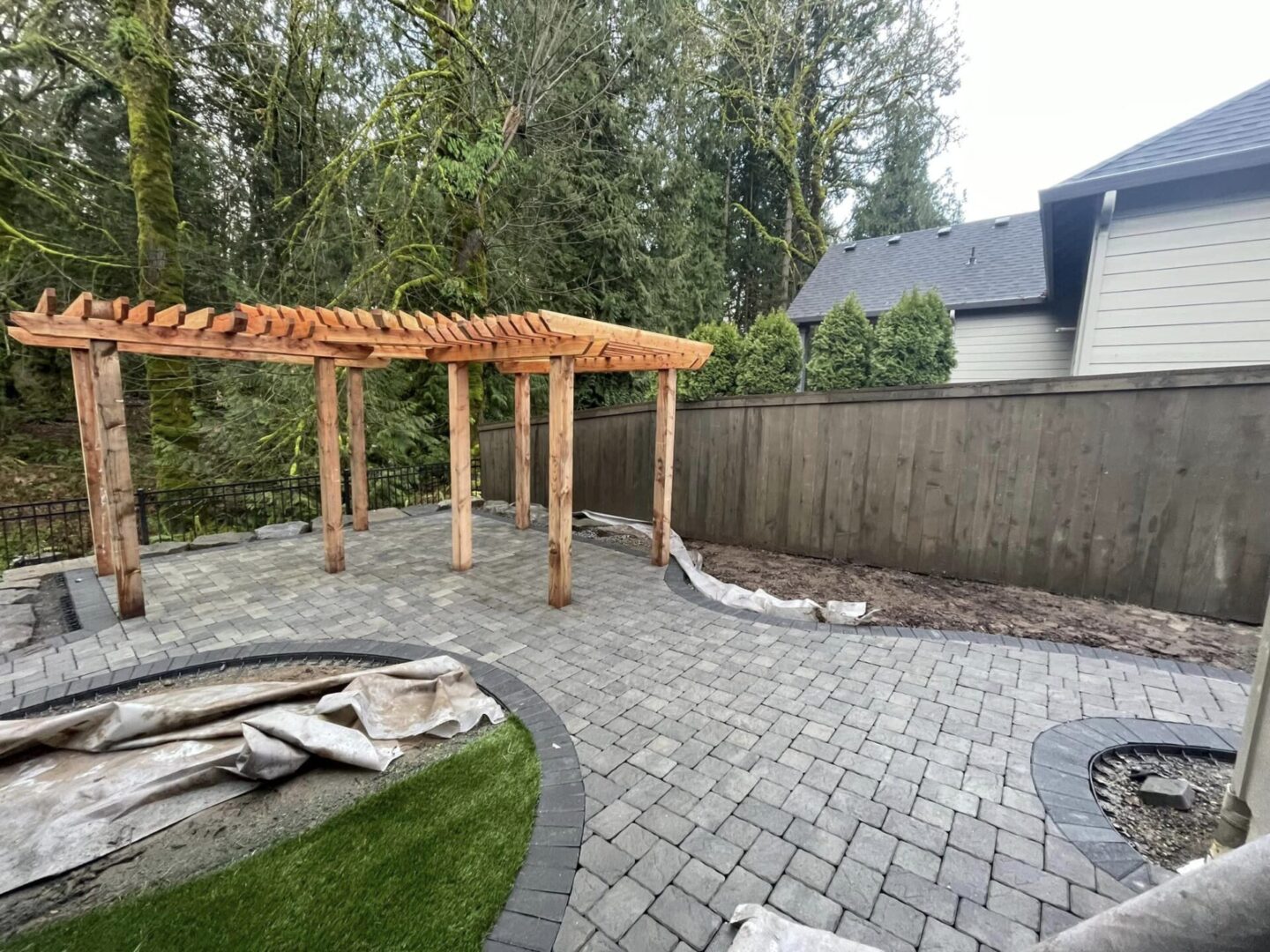 A patio with a wooden pergola and brick pavers.