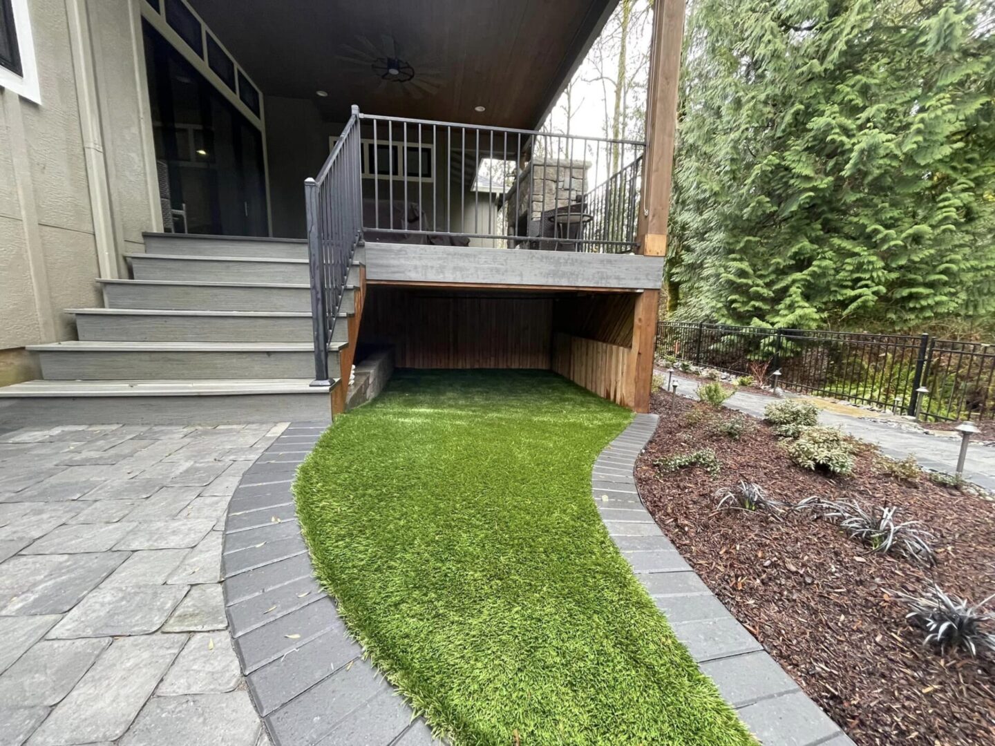 A patio with stairs and grass on the ground.