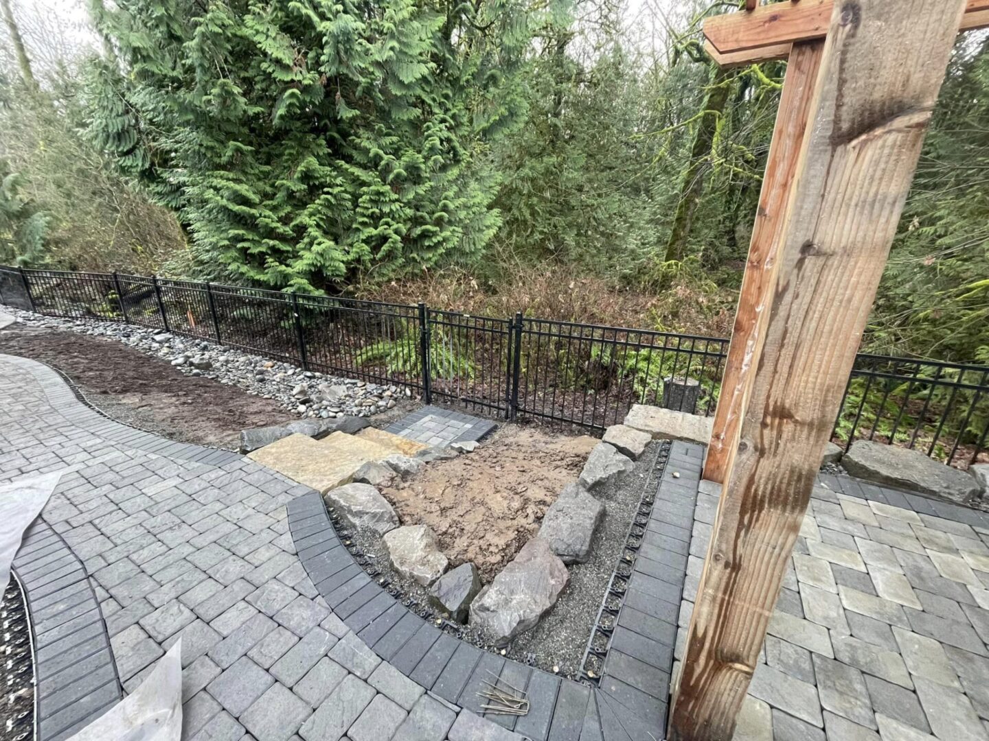 A brick patio with stone steps and a fence.