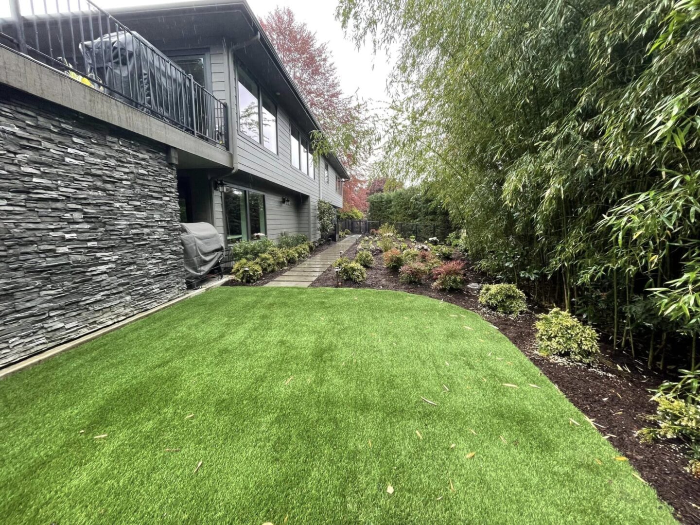 A large yard with grass and shrubs in the background.