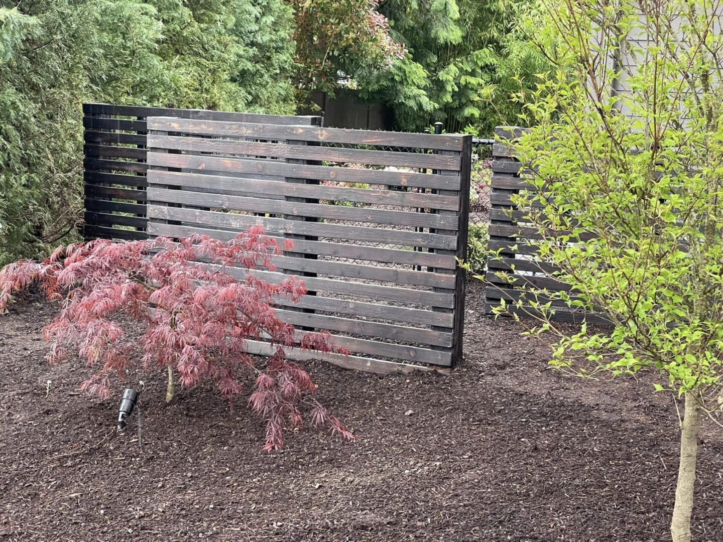 A wooden fence in the middle of a garden.