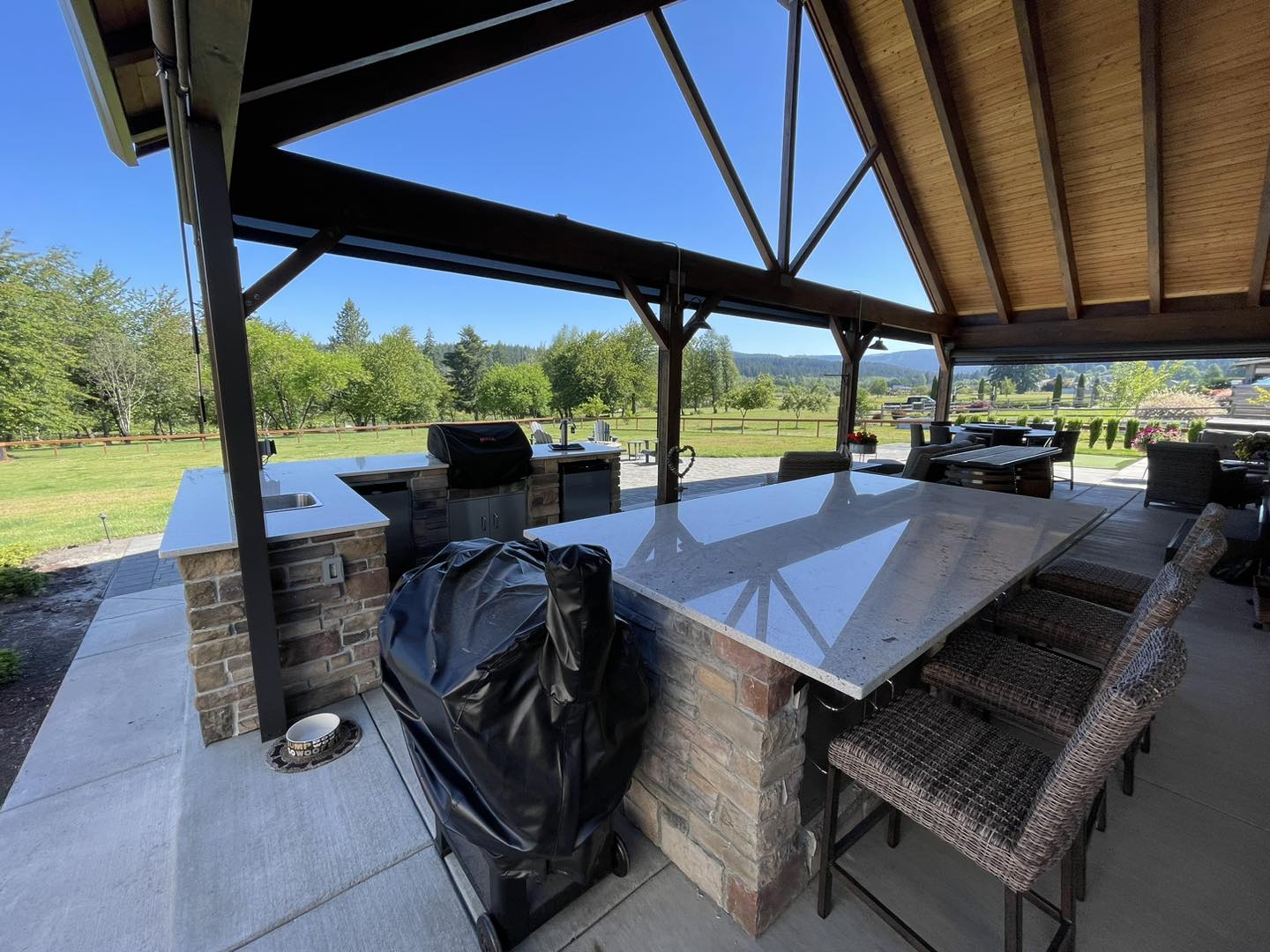 A large outdoor grill and table in the middle of an open area.