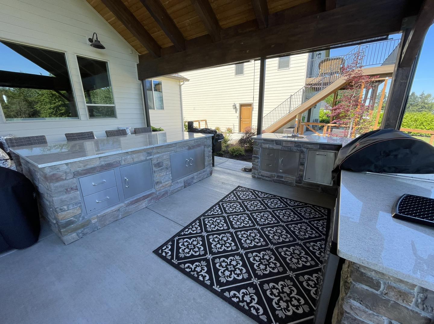 A patio with an outdoor grill and rug.